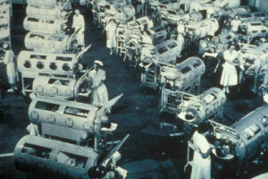 ポリオ患者が使う鉄の肺で埋まった病棟。鉄の肺が数十台並んでおり、7人の看護婦が患者の世話をしている。1953年、カリフォルニア州、Rancho Los Amigos 国立リバビリテーションセンター（当時はRancho Los Amigos 病院)